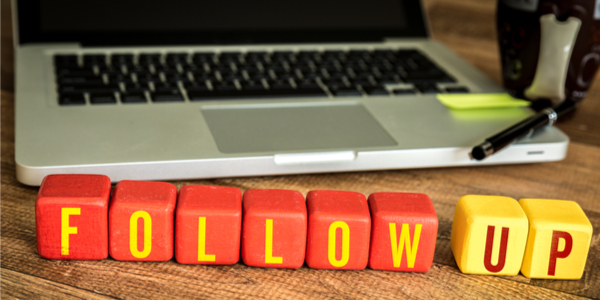 Follow Up written with wood blocks in front of lap top