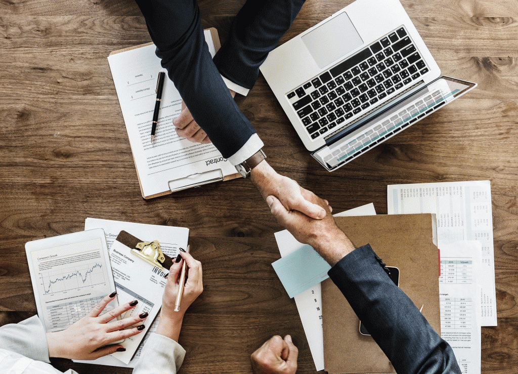Manos estrechándose sobre una mesa en una reunión de negocios para ilustrar la idea de "empresa unipersonal y sociedad"