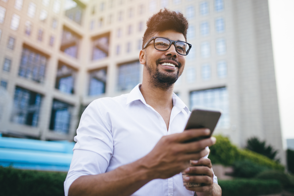 Young man in the street using cell phone on the go as his virtual office
