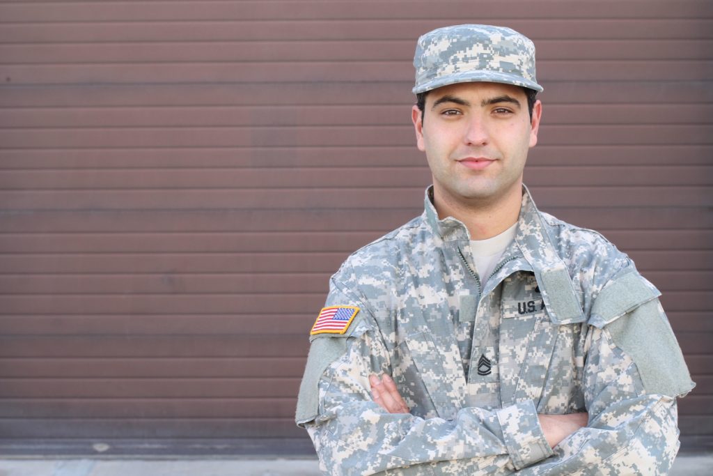Soldado hispano sonriendo a la cámara con espacio libre de fondo. paraexpresar la idea de "p´restamos comerciales pra veteranos".