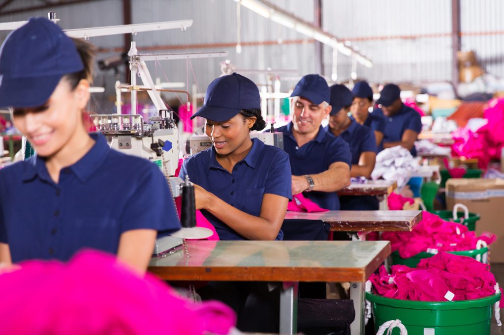 group multiracial factory workers sewing in clothing factory to illustrate "labor costs"