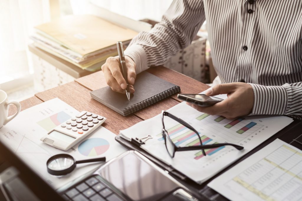 Escritorio de hombre de negocios con papeleo y calculadora para ilustrar la idea de "buro de credito"