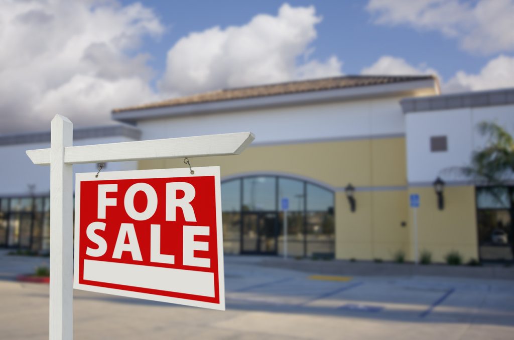 Vacant Retail Building with For Sale Real Estate Sign in Front. Concept: how to buy a business.