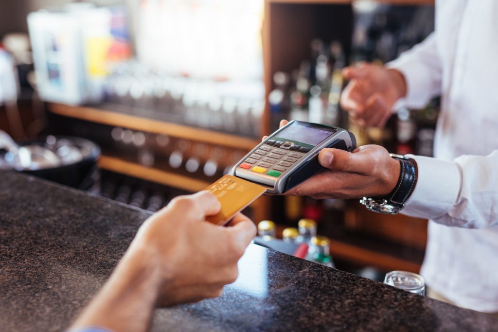 Customer making payment using credit card. Close up of card payment being made between customer and bartender in cafe. Concept: How to avoid identity theft