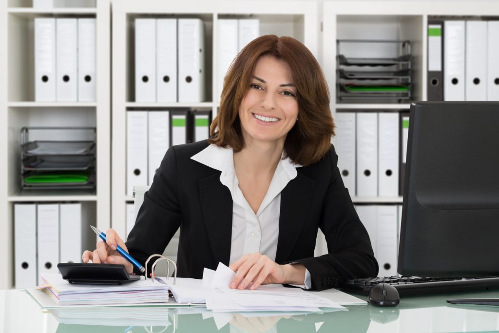 Mujer contable realizando inpuestos sentada en el escritorio en su oficina. Cómo hacer crecer tu empresa de contabilidad con un préstamo comercial
