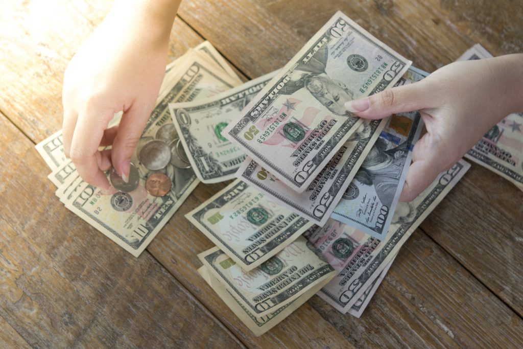 Hands counting dollar bills and coins on table. Concept: capital resources