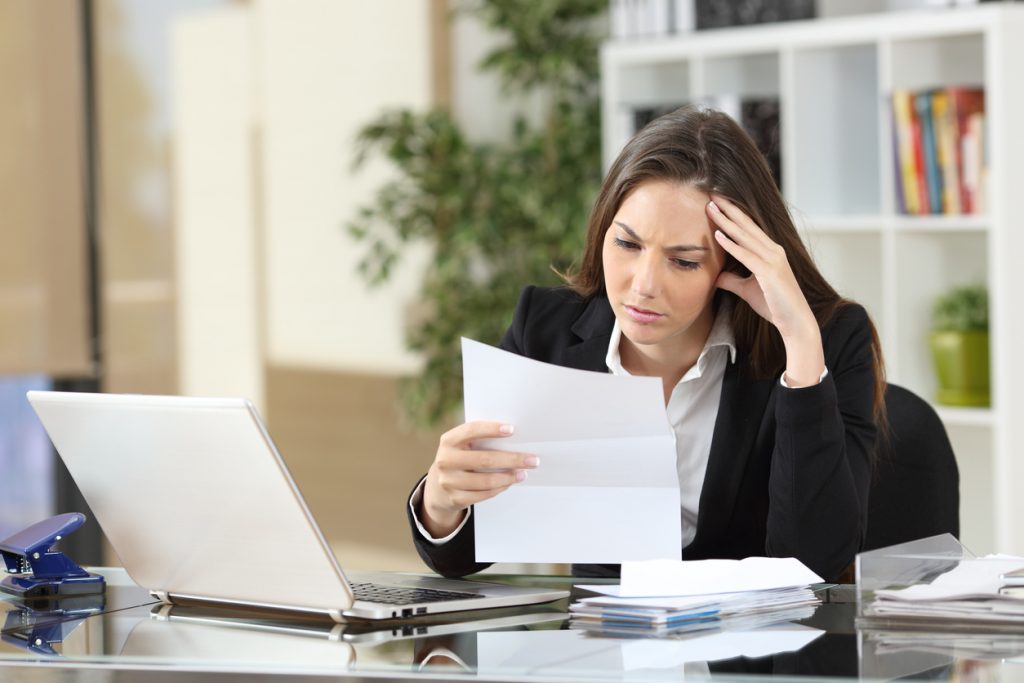 Worried businesswoman reading a notification sitting in a desktop at office. Concept: business loan declined