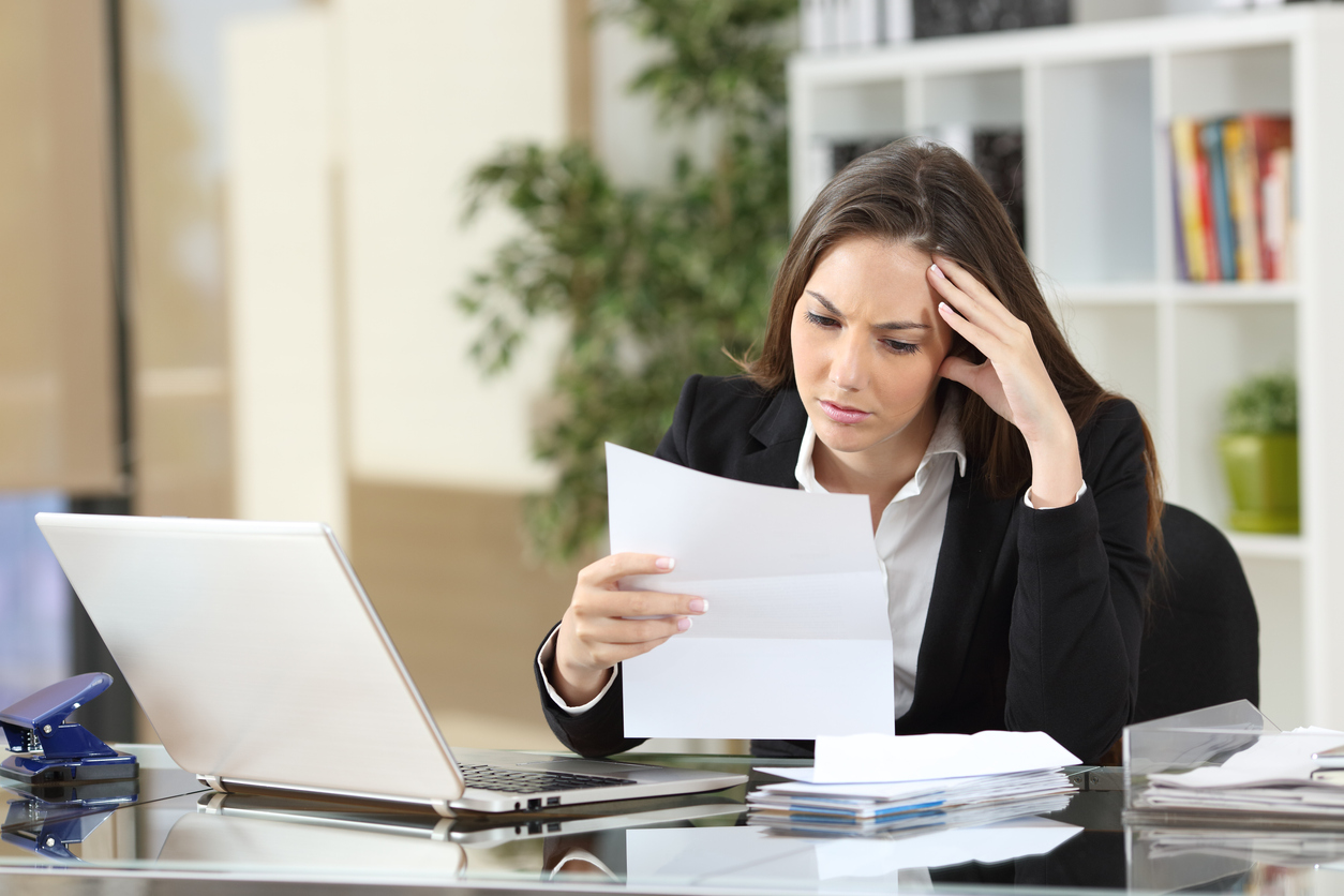 Worried businesswoman reading a notification sitting in a desktop at office. Concept: business loan declined
