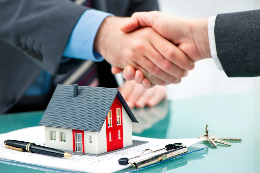 Estate agent shaking hands with customer after contract signature. Concept: difference between loan and mortgage