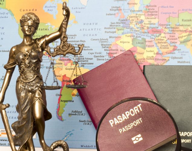 Estatua de la justicia, pasaportrs y lupa con fonde de mapa mundial. Concepto: ayuda para inmigrantes: recursos legales