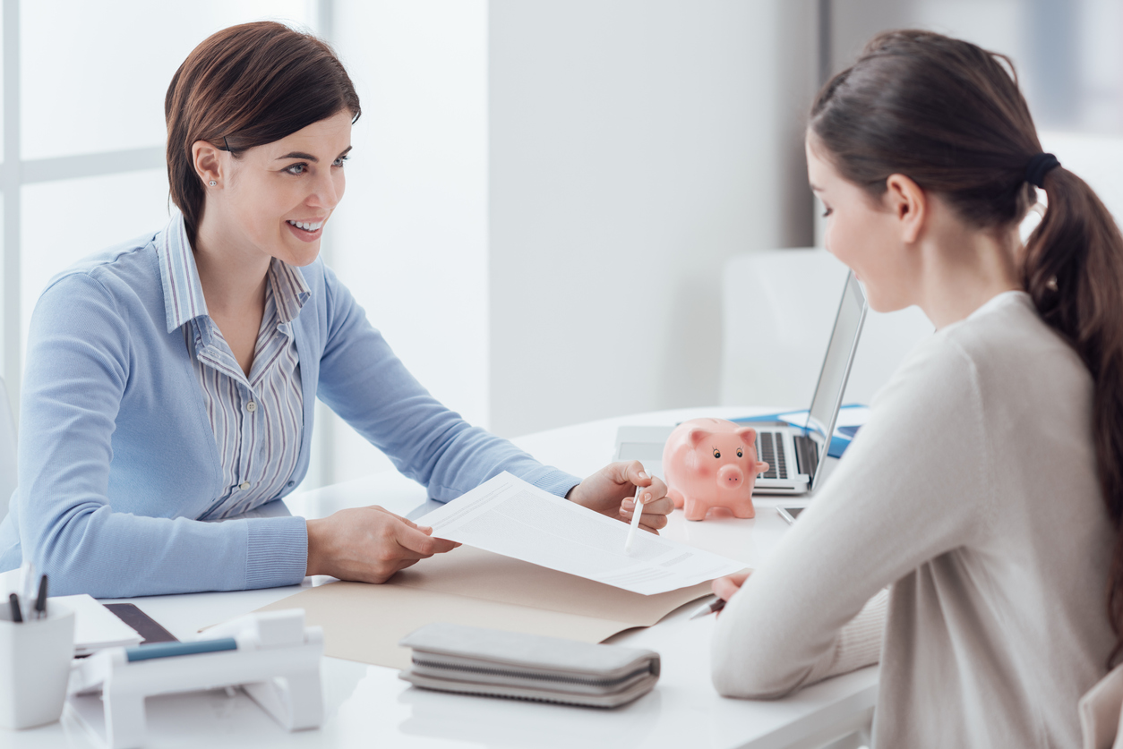 Profesional de impuestos y cliente reunidas en una oficina, y revisando documentos relacionados con impuestos. Concepto: dónde preparar impuestos