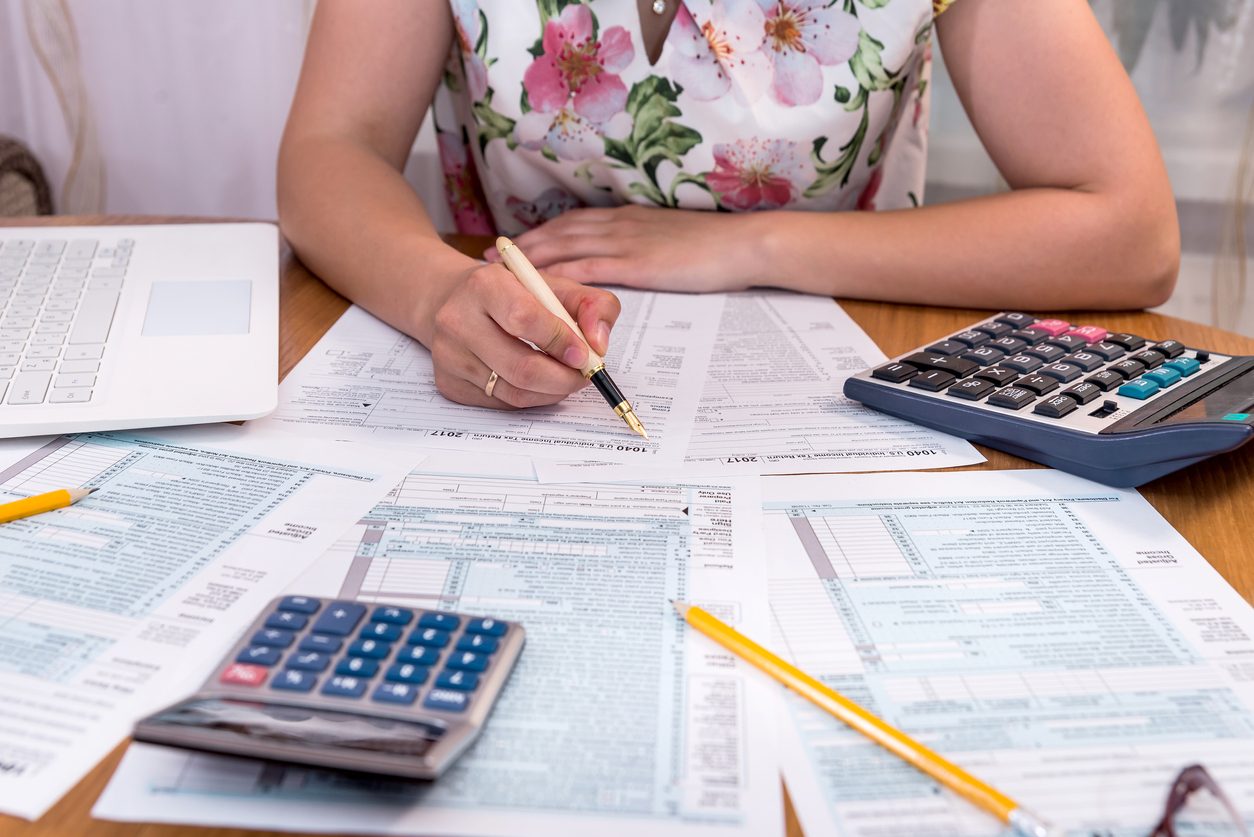 Mujer rellenando formulario 1040 sobre escritorio. Concepto: deducibles de impuestos.