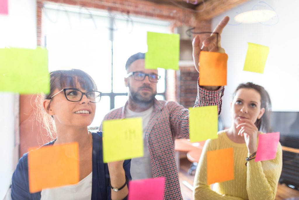 Business people brainstorming session at office using post it notes to share ideas. Concept: marketing ideas for you small business