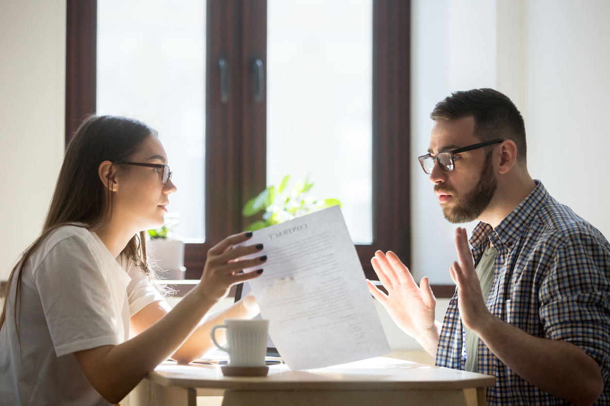 Male and female coworkers discussing in office over some documents. Concept: how to resolve conflict between employees