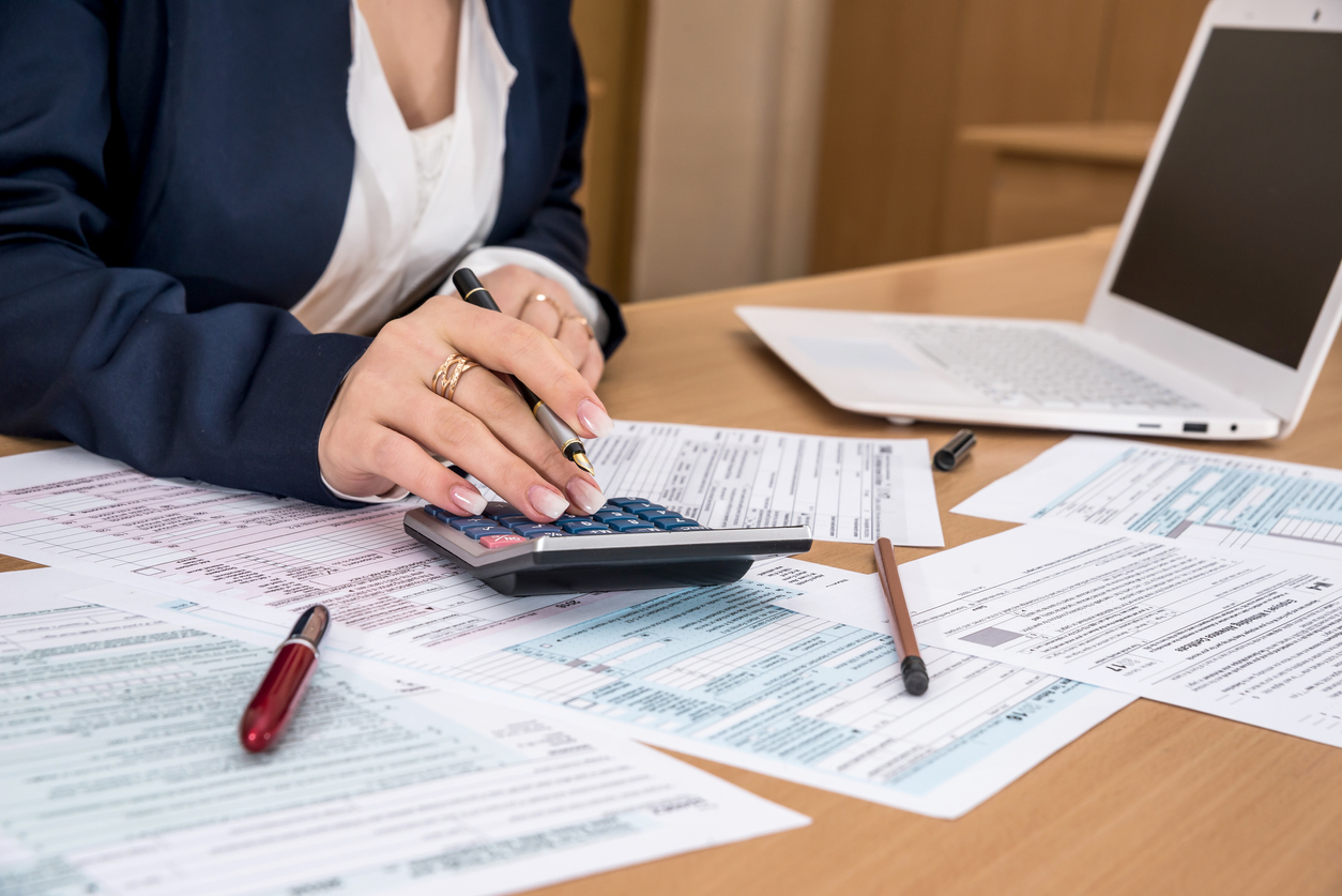 Woman torso on desk filling US tax form and using calculator. Concept: How to remove a tax lien