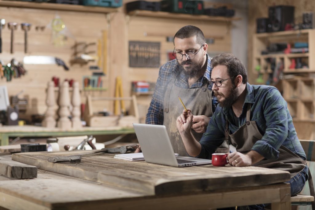 Dos dueños de taller de trabajo en madera revisando información en laptop. Concepto: Estado de flujo de efectivo