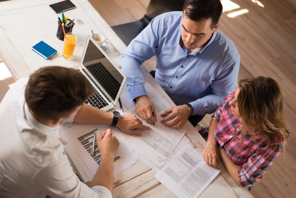 Young couple opening a business checking account in a branch with a bank representative. Concept: Best business checking accounts
