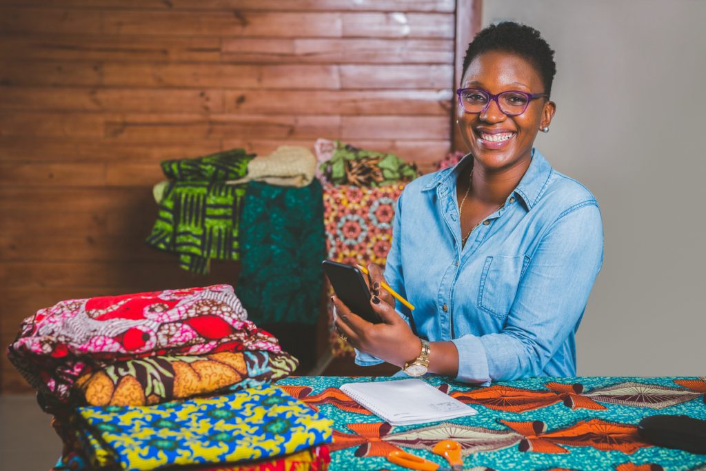 Diseñadora afroamericana en su oficina con muestras de telas coloridas sobre la mesa. Concepto: Ideas creativas para negocios