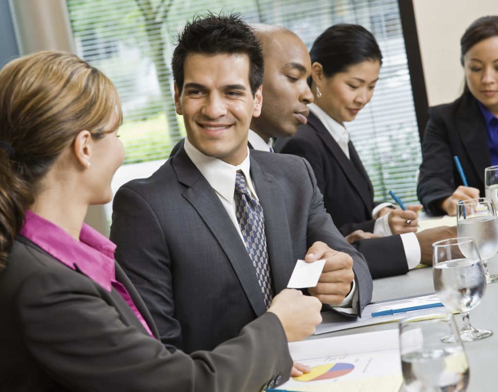 Business owner sharing his business card with a client during a meeting at his office. Concept: business cards ideas.