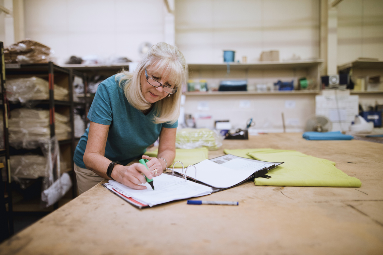 Senior businesswoman is doing paperwork in her stock factory. Concept: What is a cash flow forecast?