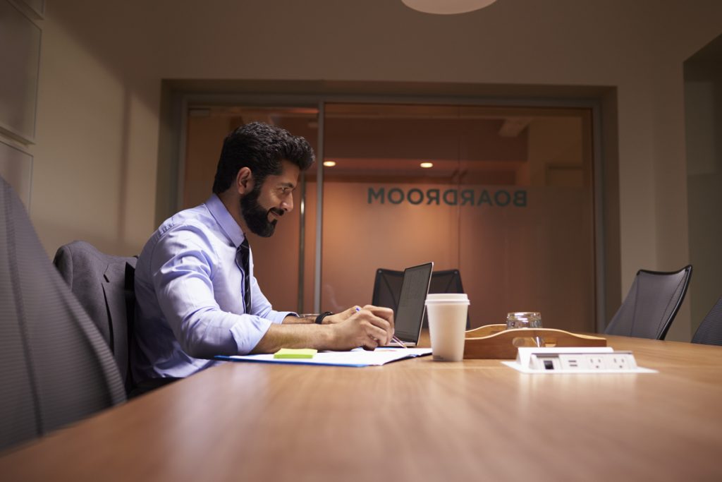 Middle aged Hispanic businessman working on laptop writing on his business blog in office. CConcept: business blog