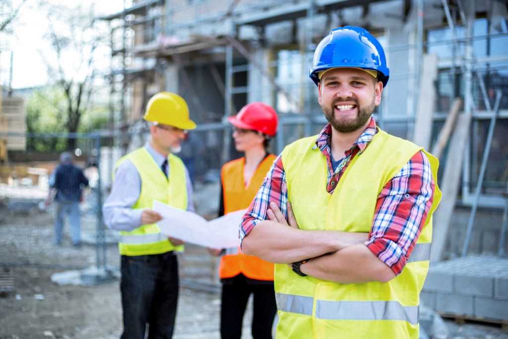 Construction business owner in construction site with crew in the background. Concept: how to improve cash flow in your construction business