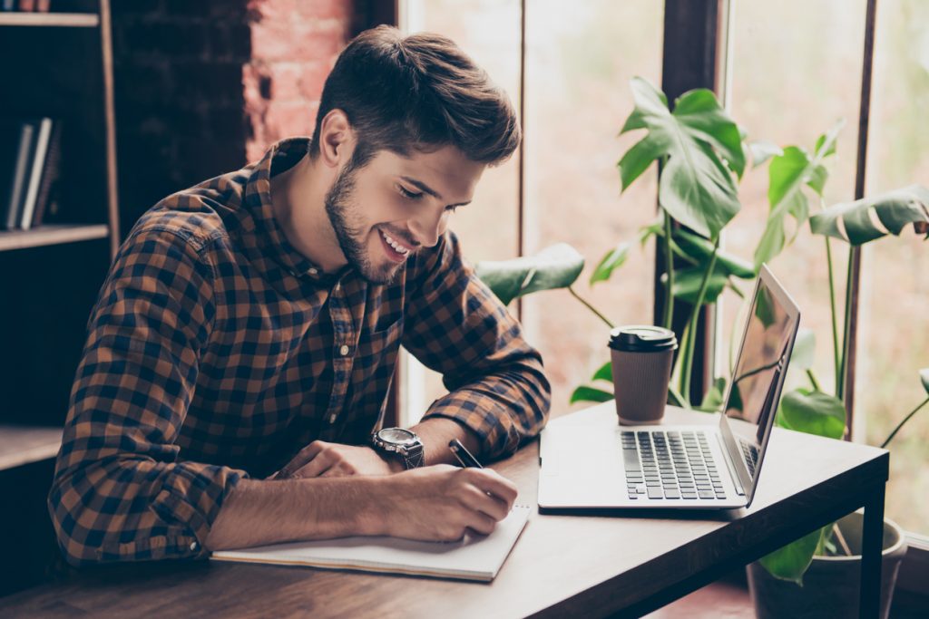 Joven empresario aprendiendo a escribir una carta de negocios sobre escritorio.