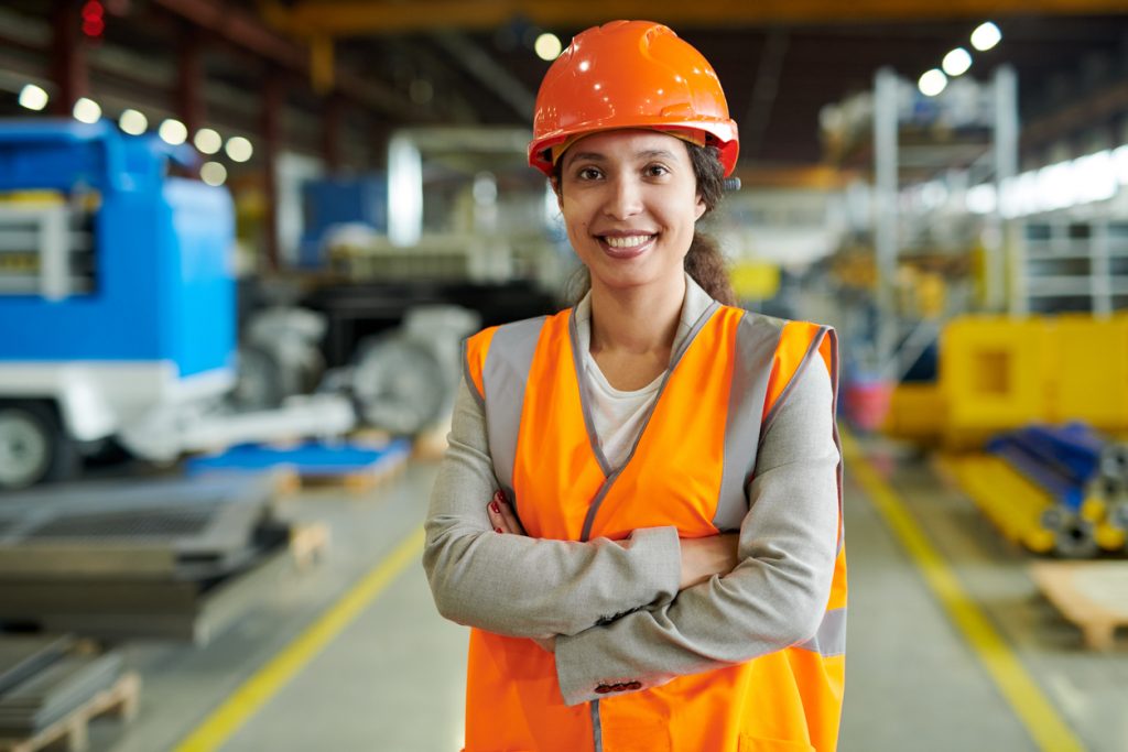 Cheerful latino woman wearing hardhat smiling happily looking at camera while posing confidently in her construction business. Concept: how to get a business loan for your construction business