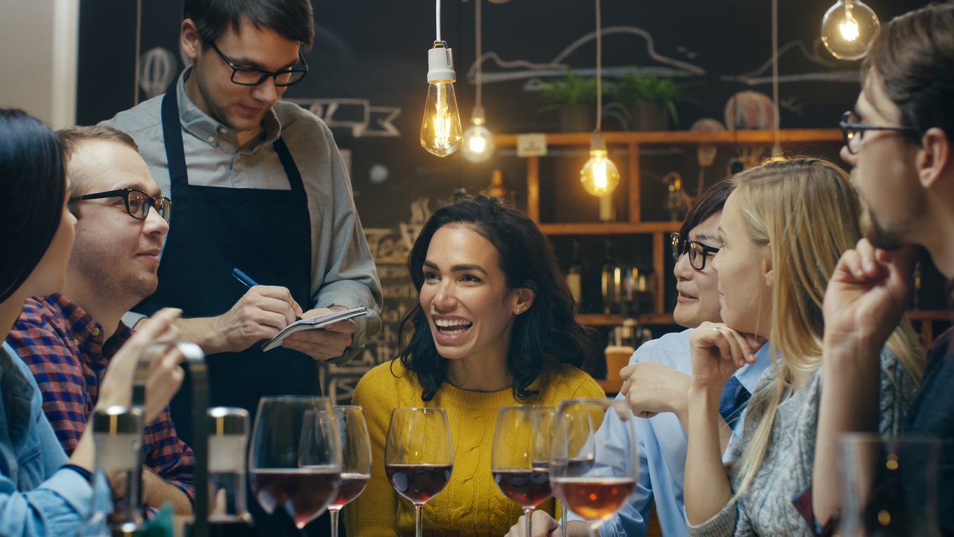 In the Restaurant Waiter Takes Order From a Diverse Group of Friends. Beautiful People Drink Wine and Have Good Time in this Stylish Place. Small Business Loan. Concept: How to get a business loan for your restaurant