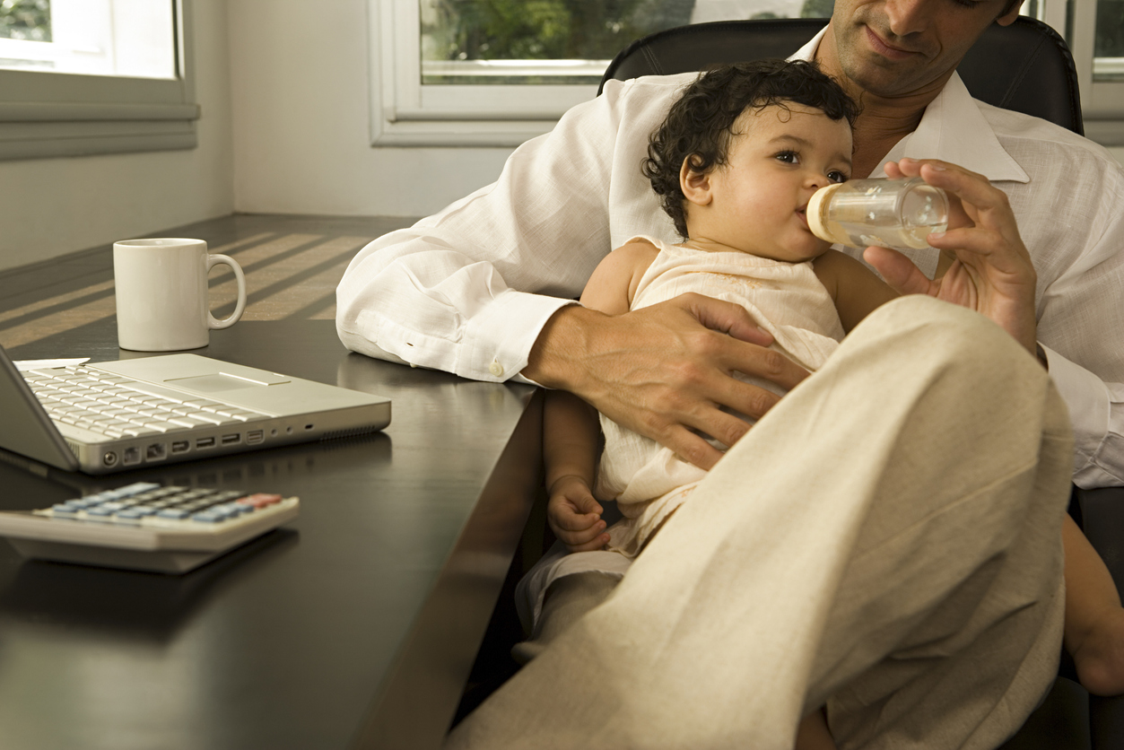 Father feeding baby in his office.Concept: Balancing fatherhood and business.