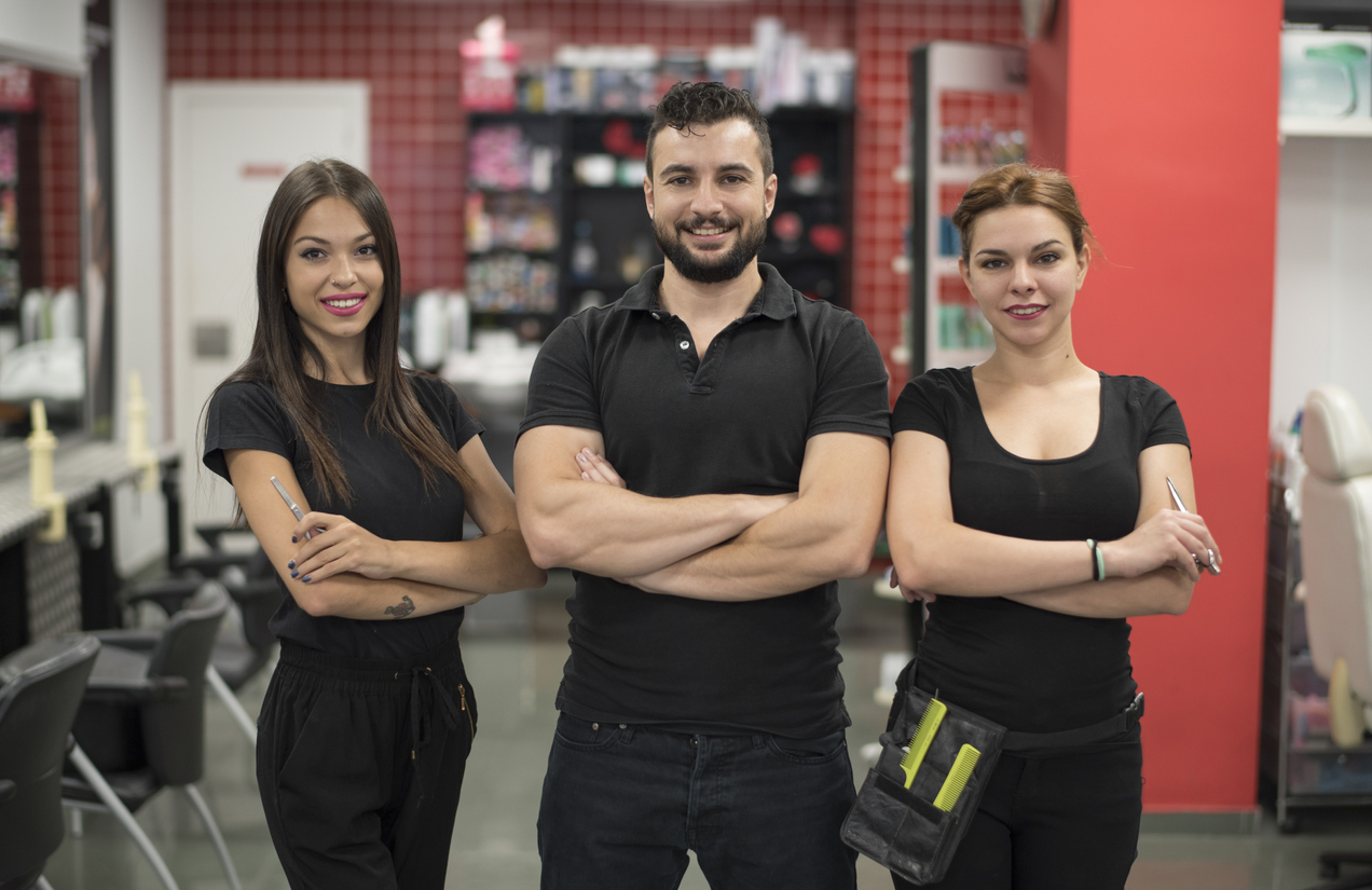 Three hairdressers in uniform posing in hair salon. Concept: Microloans vs Lines of Credit