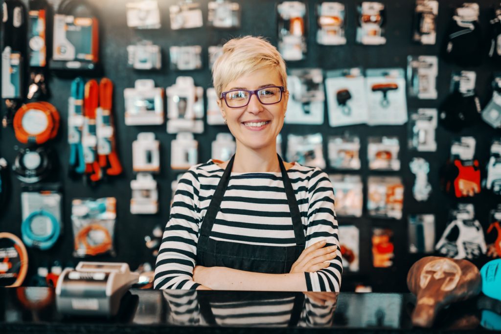 Mujer empresaria en tienda de artcículos de bicicleta, tras mostrador. Concepto: mujeres empresarias.