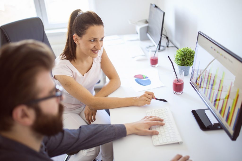 Two office workers looking at statistics together. Concept: small business statistics
