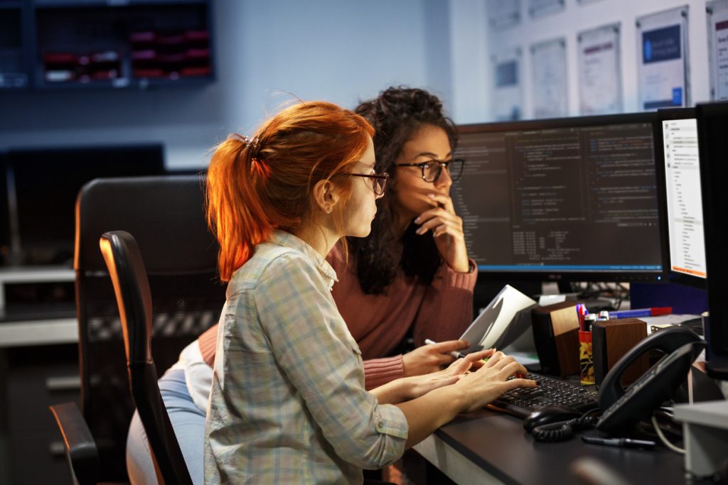 Dos programadoras trabajando en computadora. Concepto: Cómo proteger tu pequeña empresa de ataques de hackers .