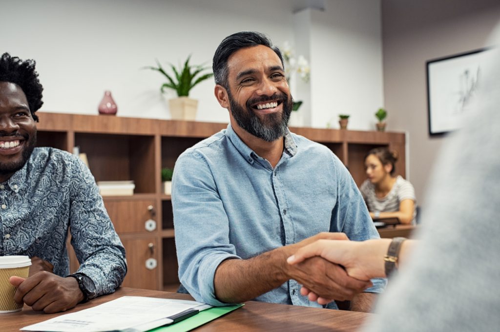 Dos emprendedores dándose la mano mientras se sientan en una sala de juntas. concept: subsidios para pequeñas empresas