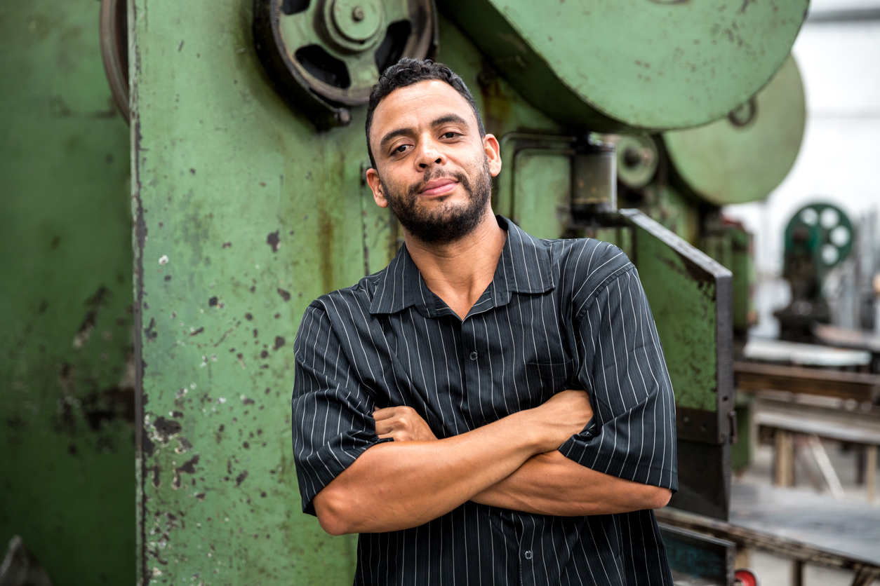 Latino worker in front of machine in factory. Concept: immigration laws
