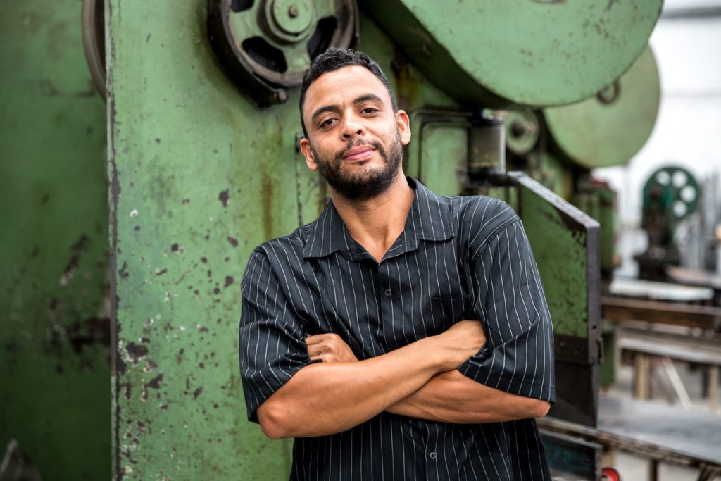 Trabajador latino frente a maquinaria en una fábrica. Concepto: leyes de inmigración.