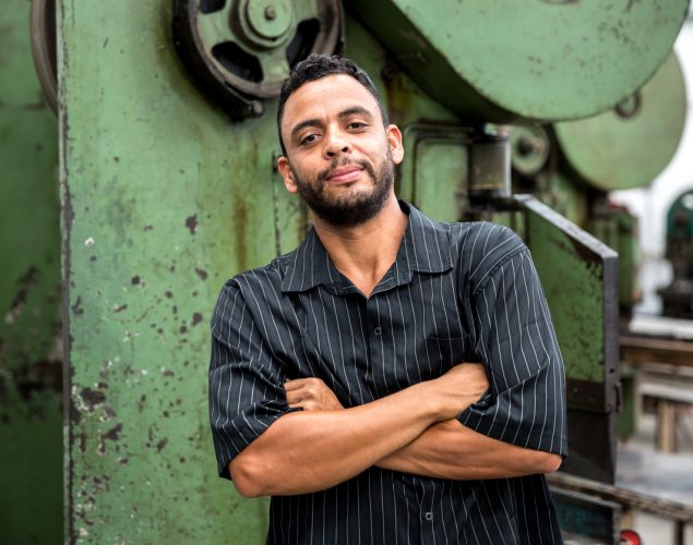Trabajador latino frente a maquinaria en una fábrica. Concepto: leyes de inmigración.