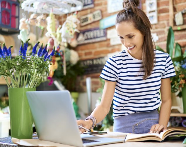 Florista trabajando en laptop y anotando en un cuaderno. Concepto: marketing de contenido.