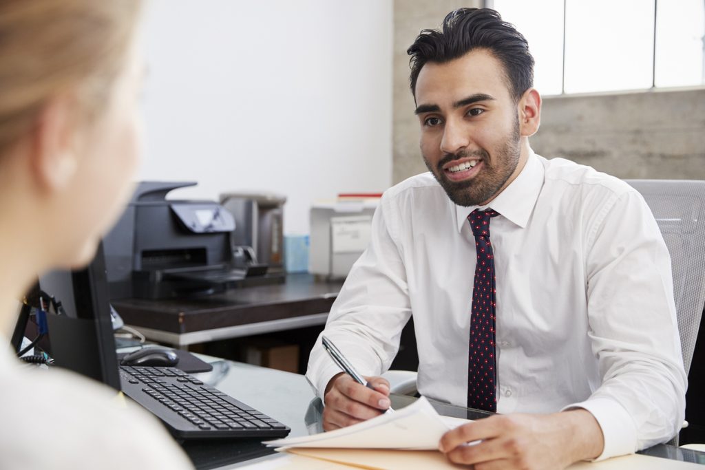 Young Hispanic male professional in meeting with woman in office. Concept: bookkeeping