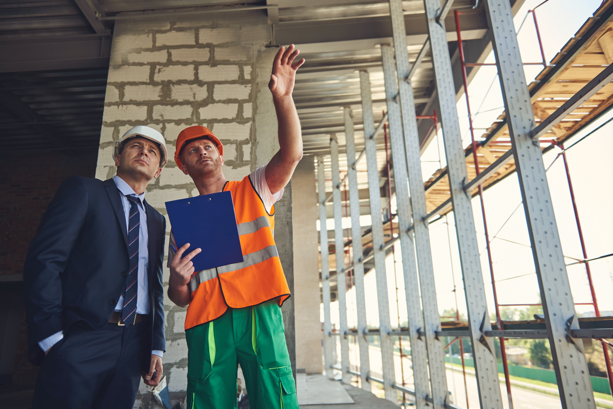 Worker man is showing to project manager completed design on construction site. Concept: business plan for construction company