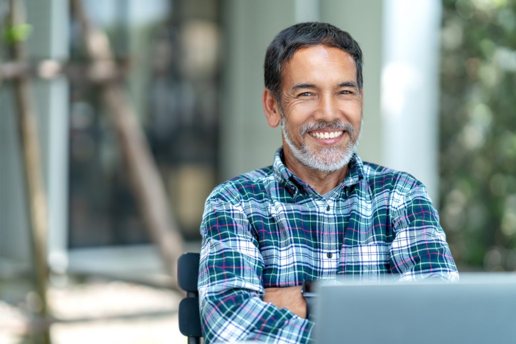 Portrait of happy mature man with white, grey stylish short beard looking at camera outdoor. Casual lifestyle of retired hispanic people or adult asian man smile with confident at coffee shop cafe. Concept: start a business as an immigrant