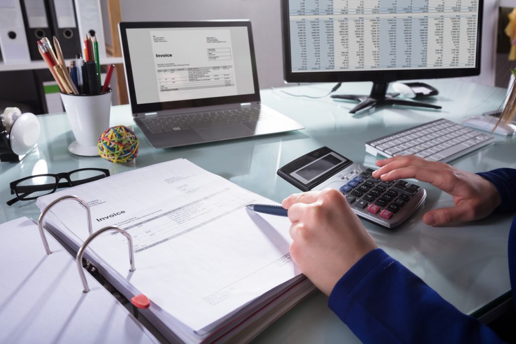 Close-up de un empresario calculando impuestos en su oficina, con calculadora y computadora. concept: mejores software de impuestos