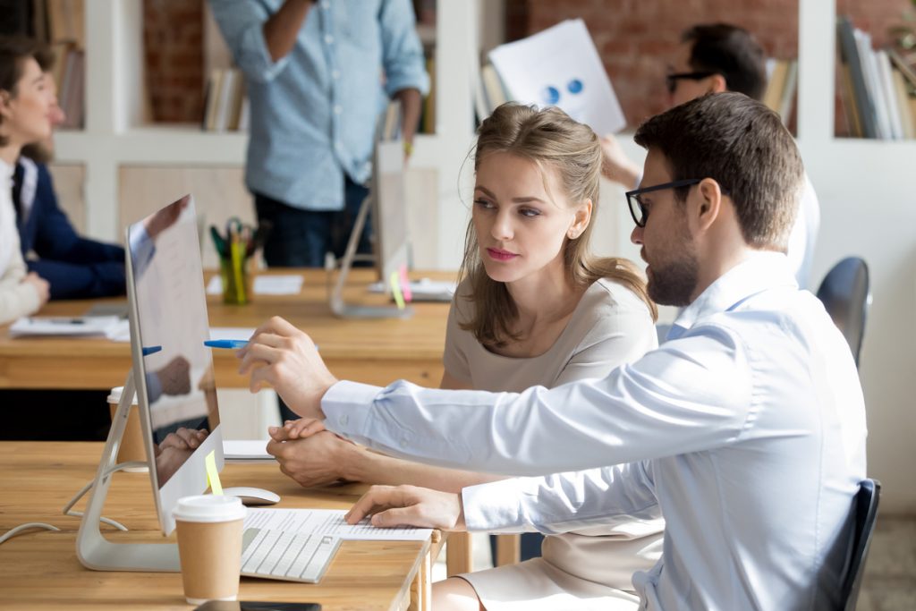 Empleados trabajando frente a computadora en oficina. Jefe enseñando a empleada como usar un programa de computadora. Concept: Descuentos de software de impuestos