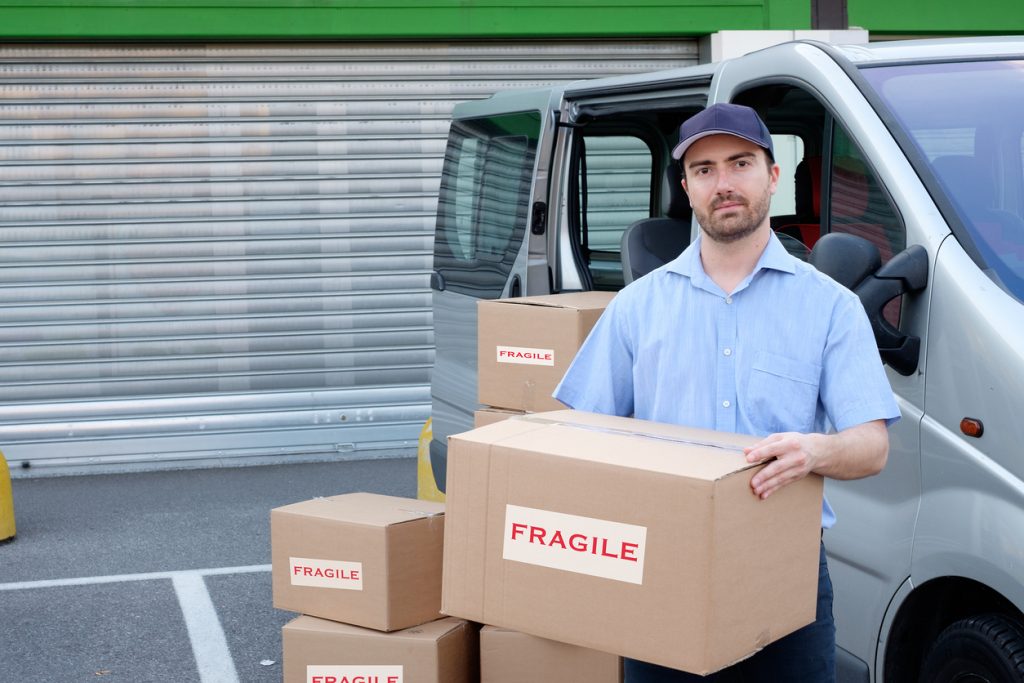 Repartidor con cajas junto a camioneta de reparto. Concepto: Seguro de auto comercial o seguro de auto personal