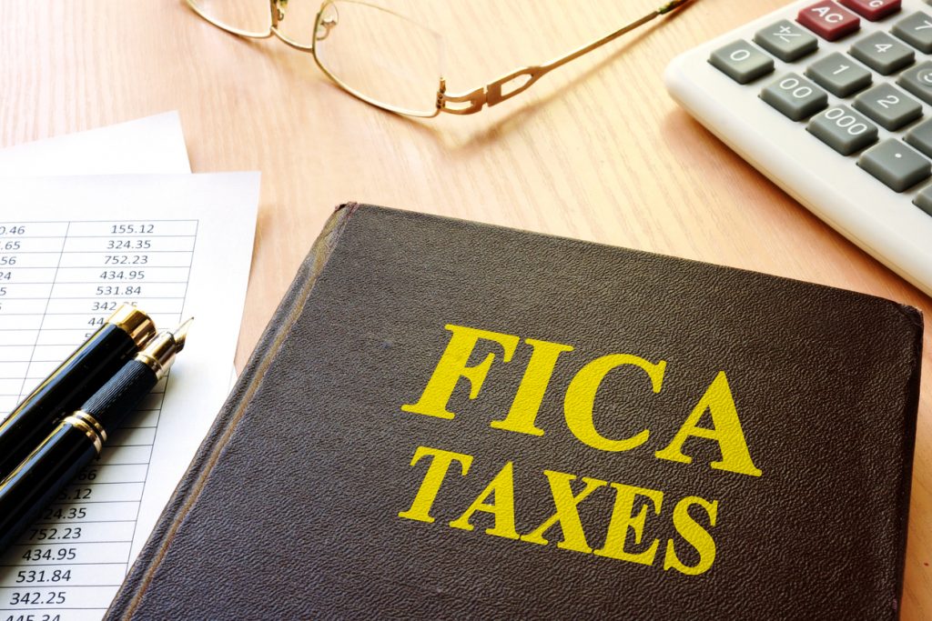 FICA Taxes and calculator on a table. concept: what are FICA taxes?