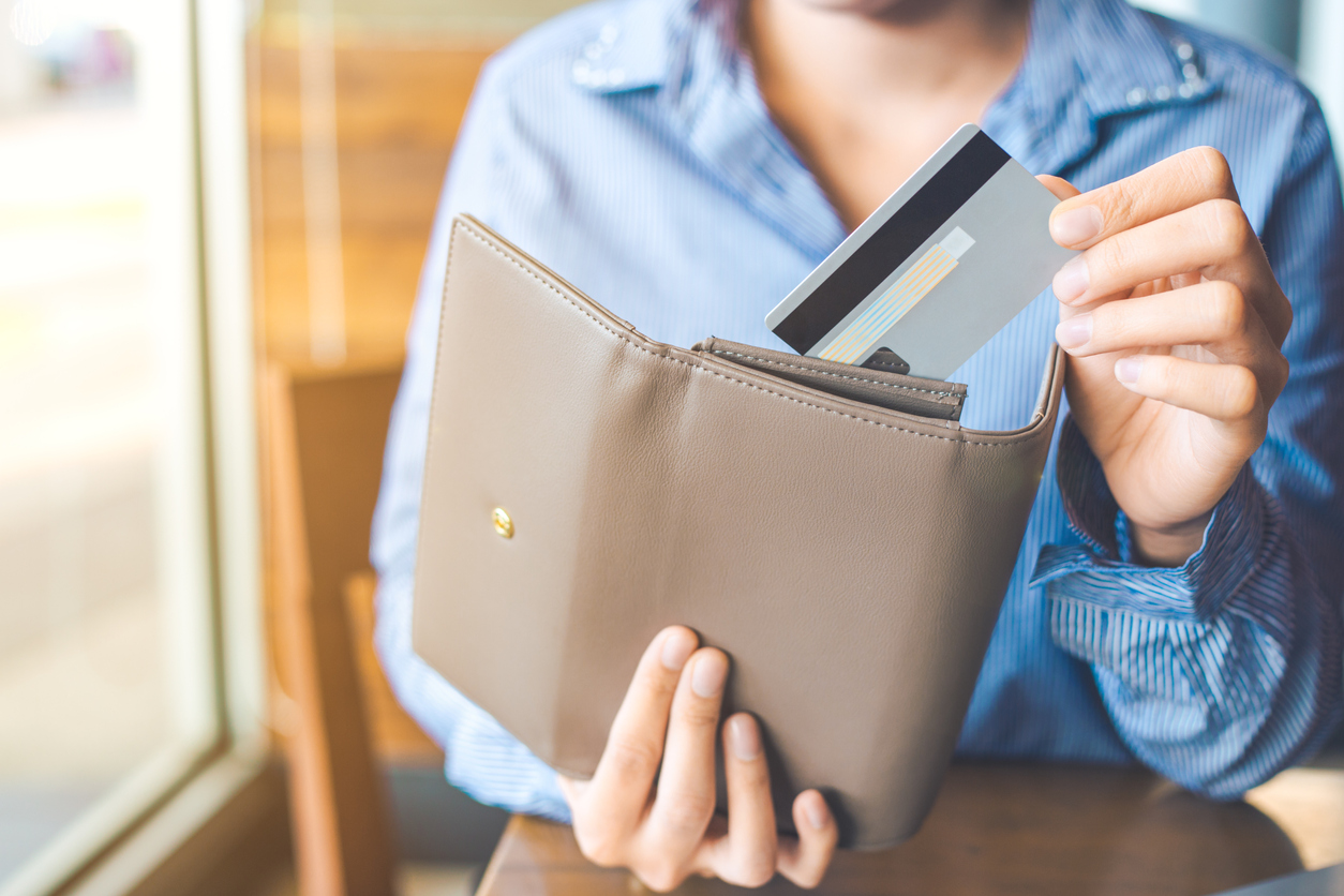 Women's hand pulling one of the best secured credit cards out of her wallet.