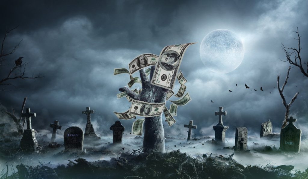 Mano de un muerto viviente saliendo de la tumba en cementerio con niebla y billetes. Concept: deuda zombie
