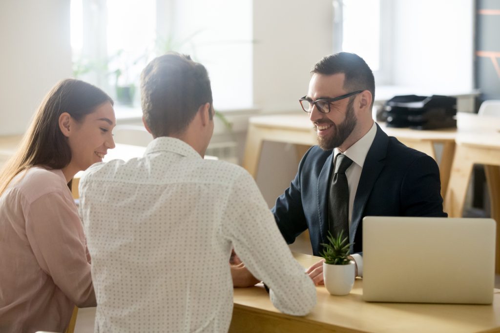 Abogado o consultor financiero amigable consultando con una pareja joven. Concept: seguro contra interrupción de actividades comerciales