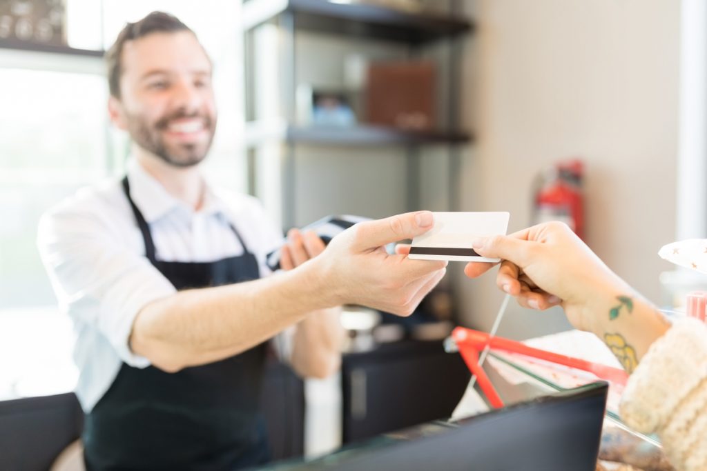 Manos de un cliente pagando a vendedor con una tarjeta de crédito en una panadería. concept: tarjeta prepagada